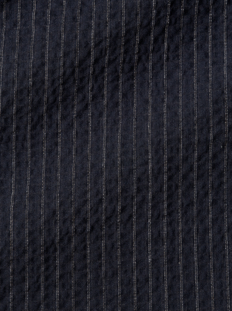 A pair of navy pleated trousers with a straight-leg cut, crafted from soft stretch cotton denim with front and rear pockets.