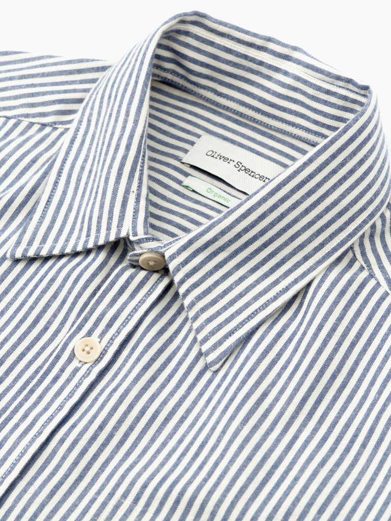 Close-up of a blue and white striped shirt with a brand label on a white background.