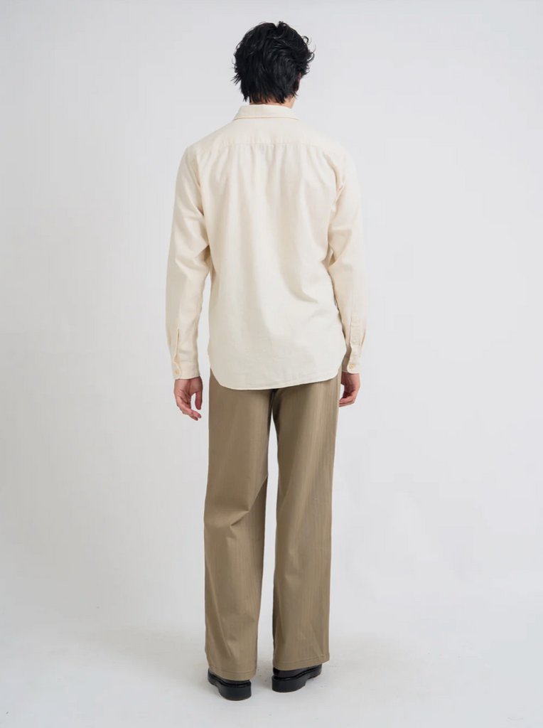Person wearing a cream shirt and beige pants on a white background.