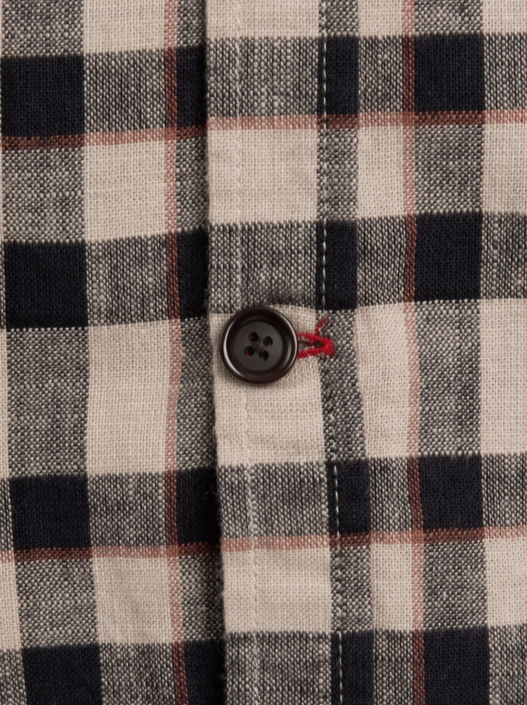 Close-up of a plaid fabric with a button on a checkered pattern.