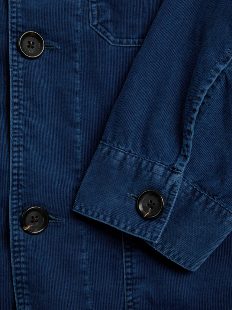 Close-up of a blue corduroy jacket with button details.