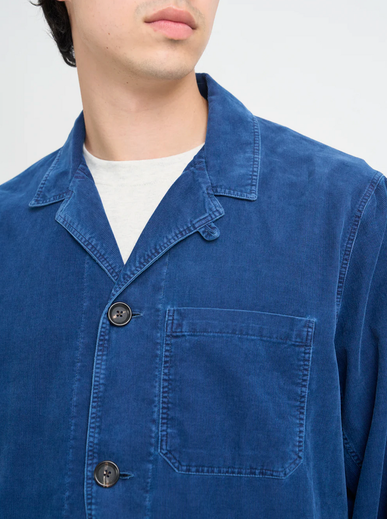Blue corduroy jacket worn by a person on a white background.