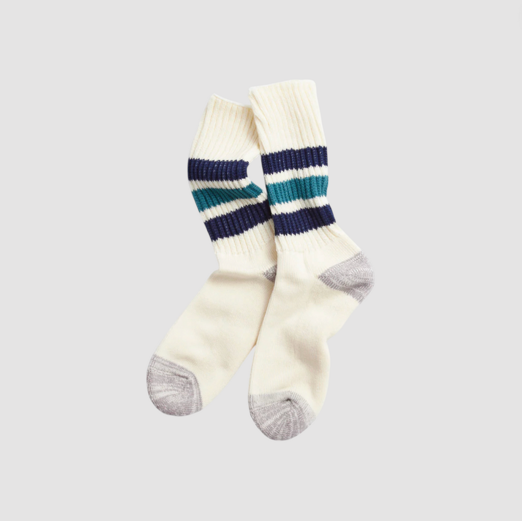 Pair of white socks with blue stripes on a light grey background. 