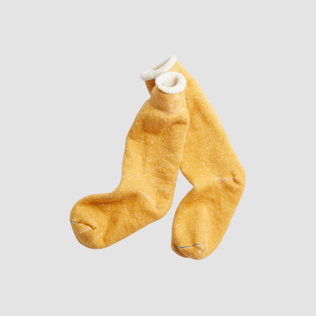 Pair of yellow cotton socks on a light grey background. 