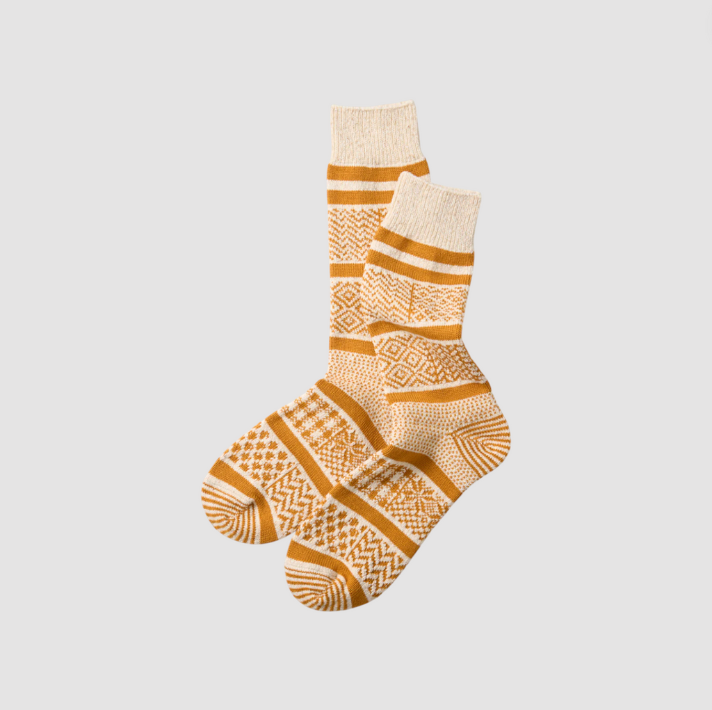 Pair of yellow and white patterned socks on a light gray background.