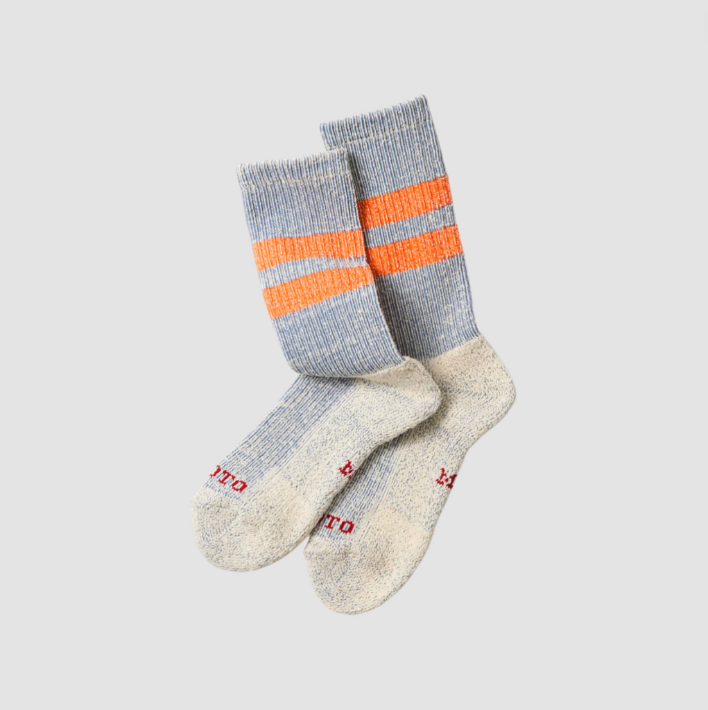 Pair of blue marl socks with orange stripes on a light gray background.