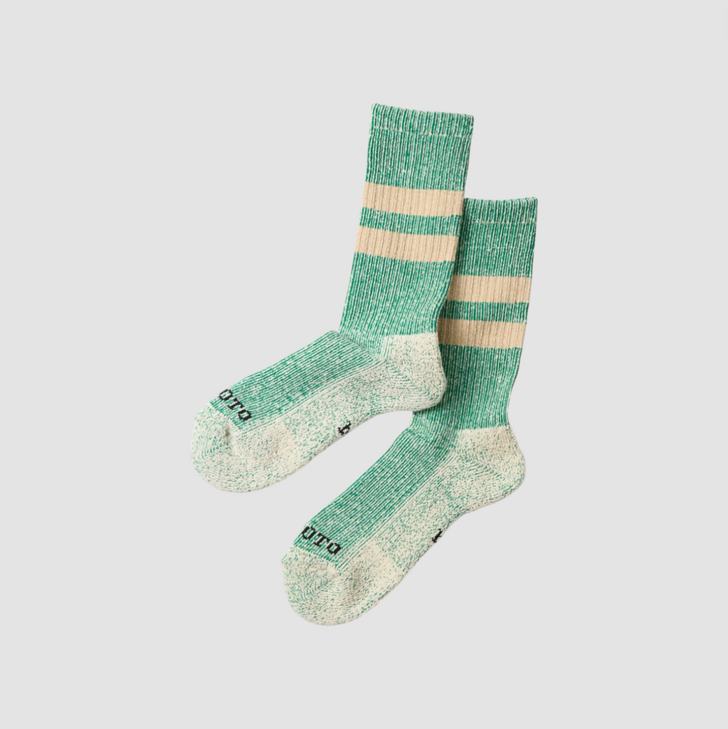 Green and beige striped socks on a light gray background.