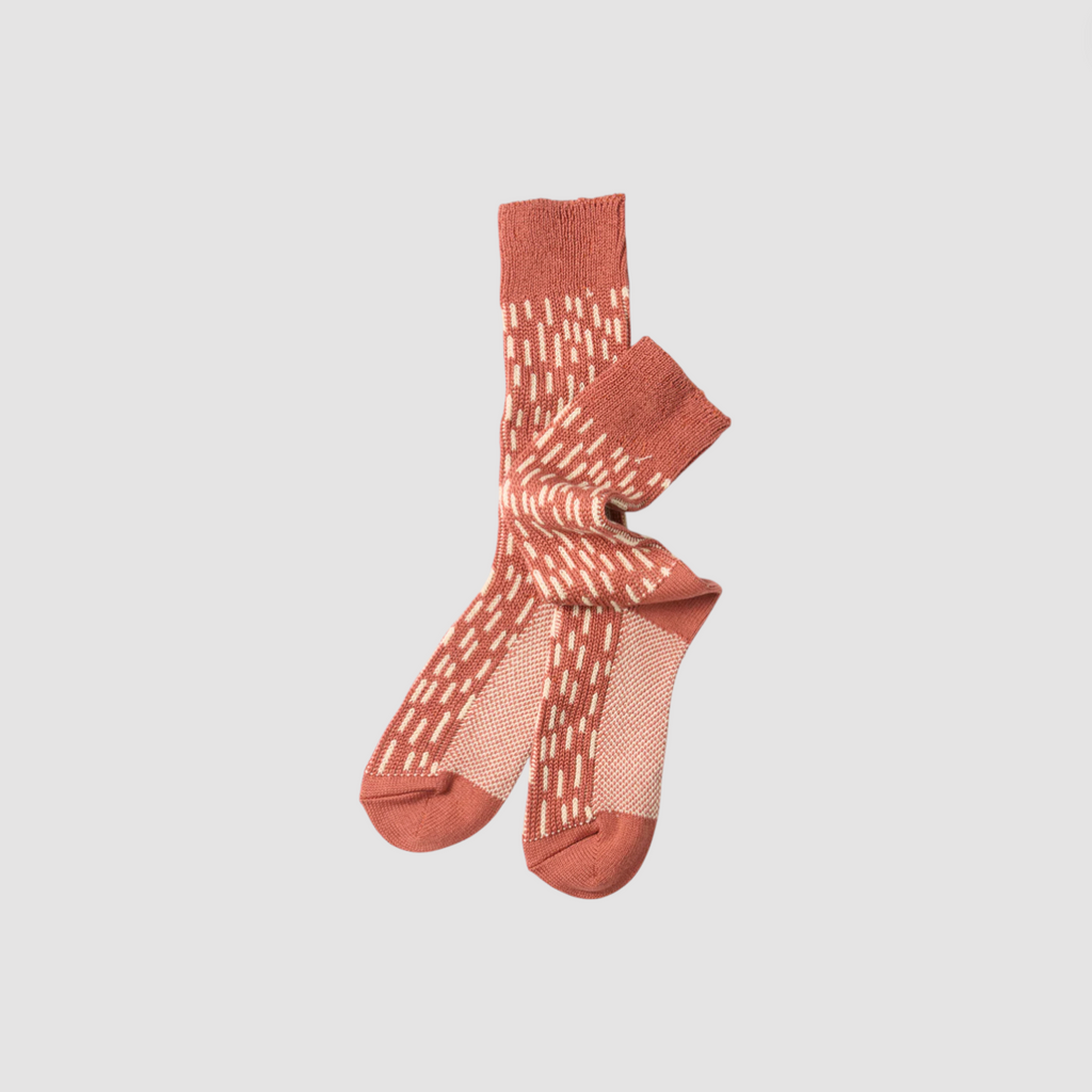 Pair of pink socks with white pattern on a light gray background.