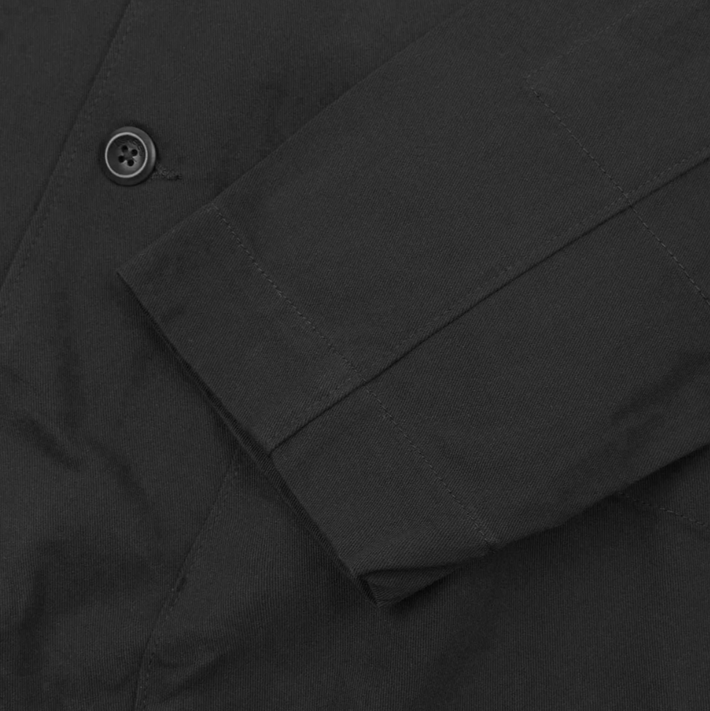 Close-up of a grey blazer with a button on a dark background. 
