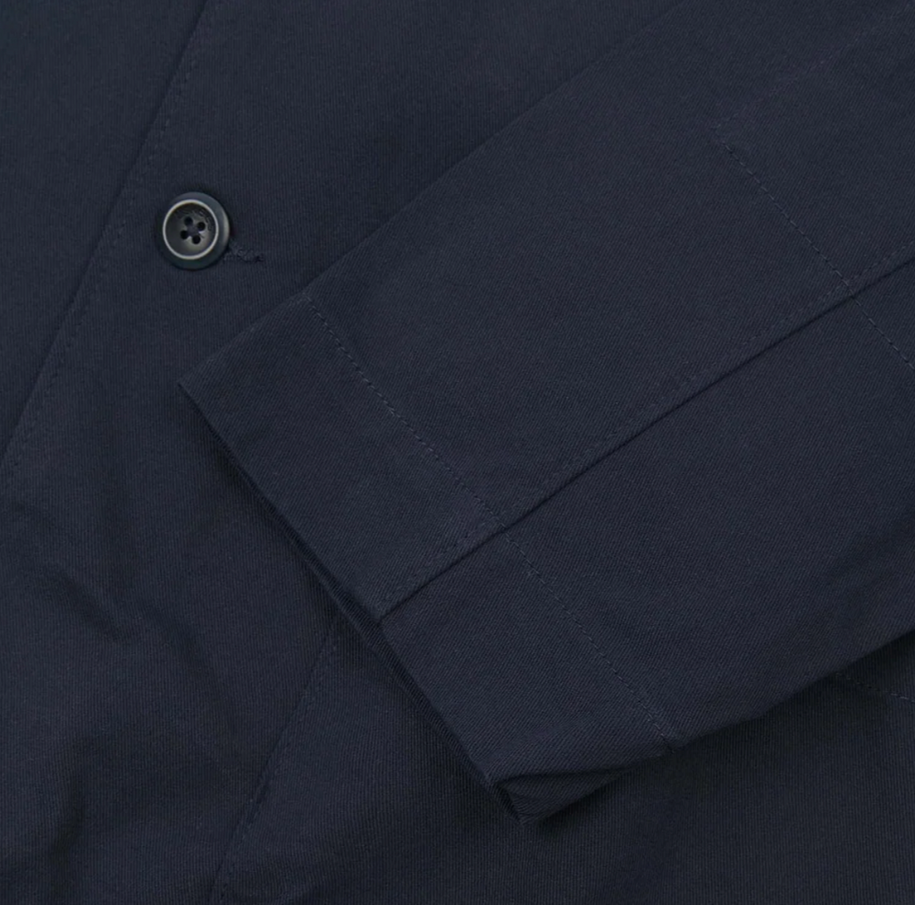 Close-up of a navy blue blazer with a button.