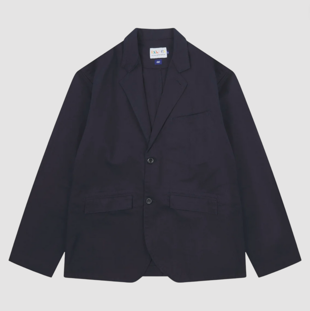 Twill blazer in midnight blue organic cotton with a two-button front, angled pockets, reinforced elbows, back vent, and plant-based corozo buttons.
