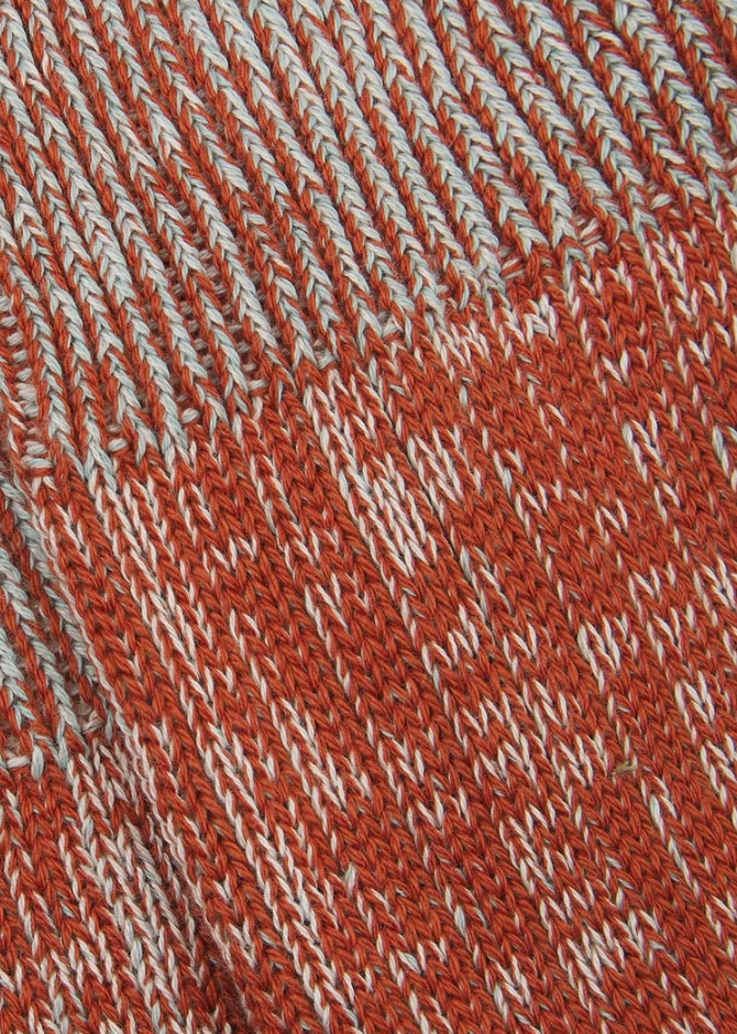 Close-up of a textured sock with a pattern of red and pale blue lines.