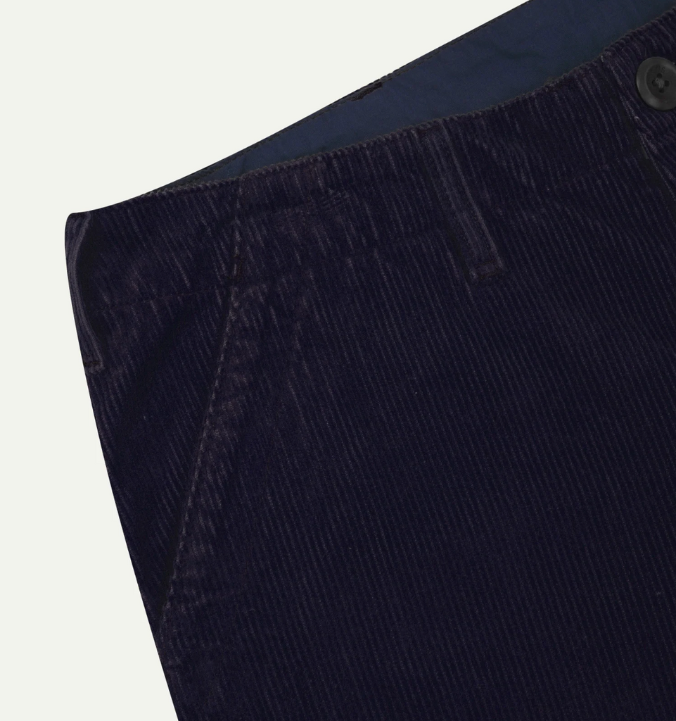 Close-up of dark blue corduroy pants on a light gray background.