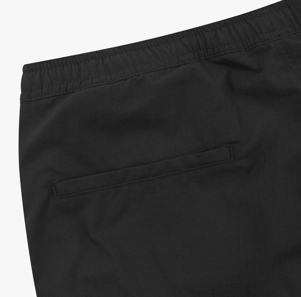 Close-up of black pants with a pocket on a white background.
