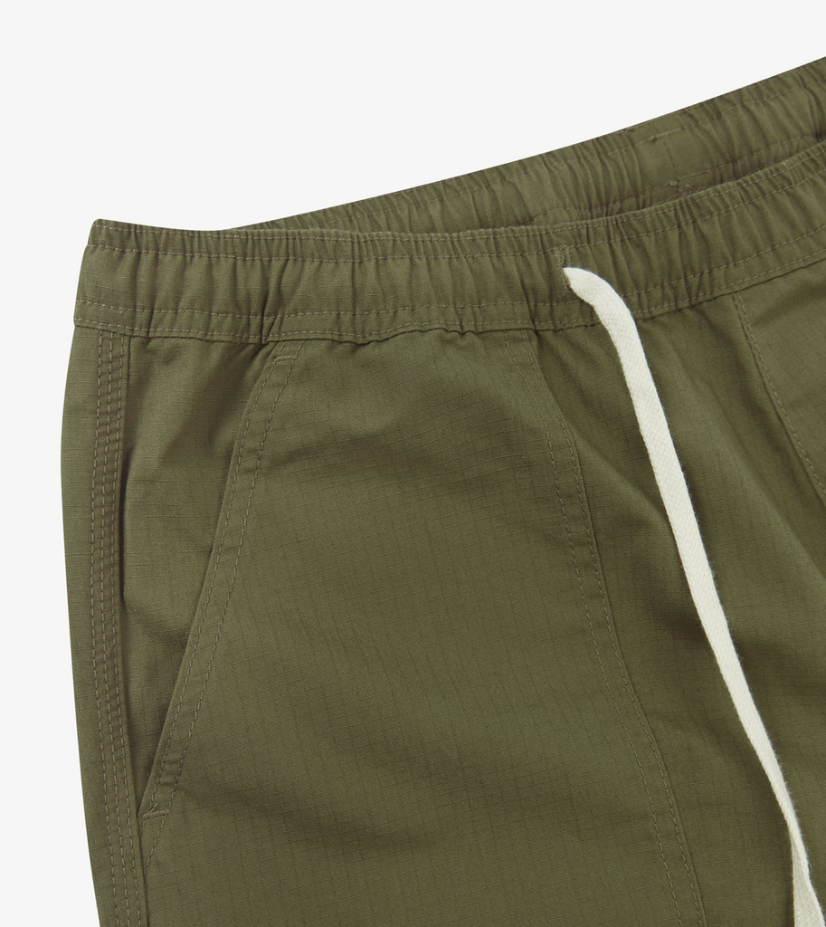 Close-up of green pants with a white drawstring on a light gray background.
