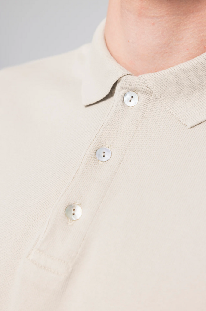 A long-sleeve polo in soft bone white, showcasing its premium organic cotton fabric.