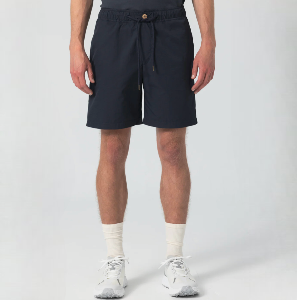 Dark navy sport shorts featuring wooden buttons, zipper closure, elastic waist, drawstring with metal aglets, and zippered side and back pockets.