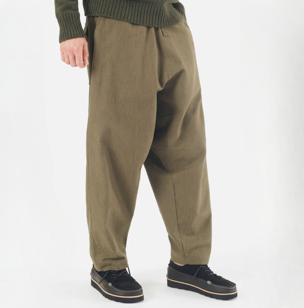 Olive green loose-fitting cotton pants with a drawstring waist, large front and back patch pockets, and wide hems. Made from durable twill weave fabric.