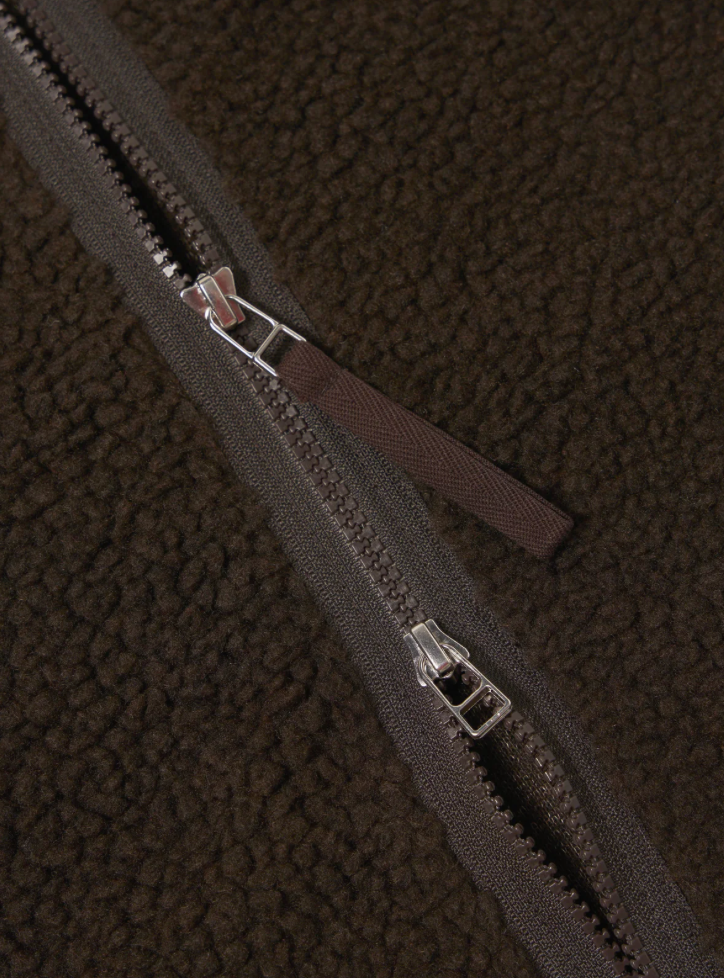 Close-up of a zipper on a textured brown fabric background.
