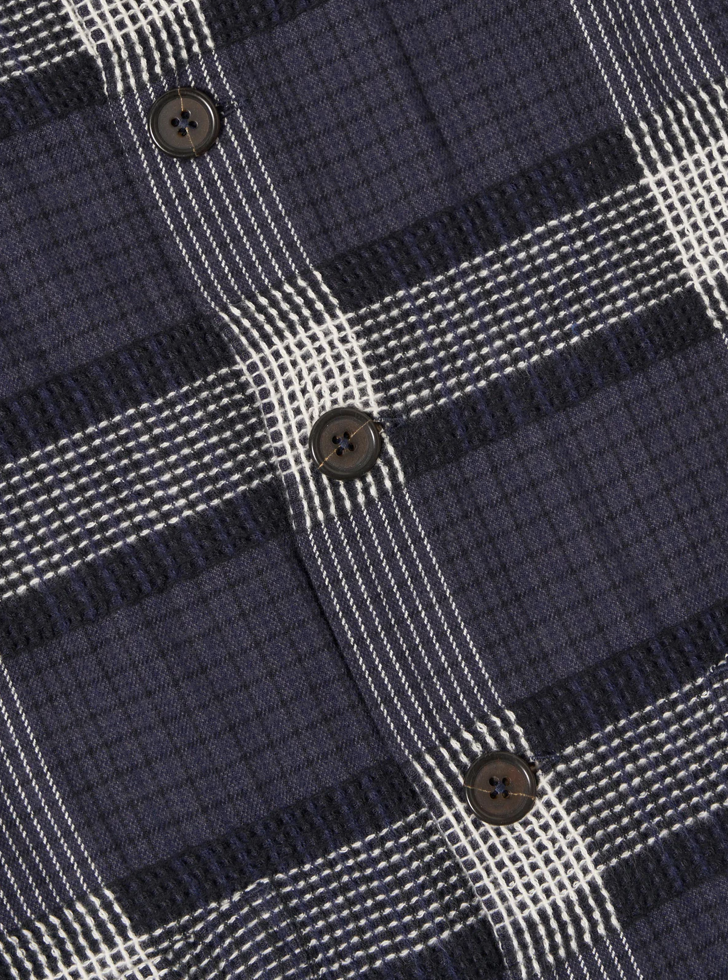 Close-up of a navy and white plaid shirt with buttons..