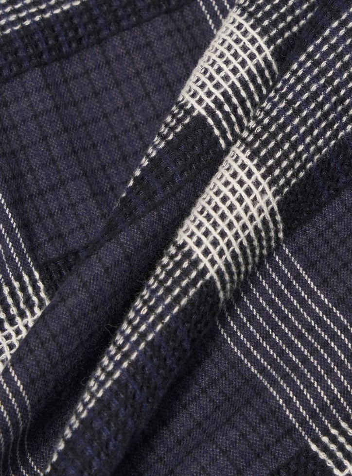 Close-up of a navy and white checkered fabric with white stitching.
