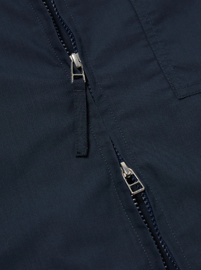 Navy boxy-fit jacket with an oversized collar, zip front, large patch pocket, welt pockets, pleated details, and an adjustable back hem.