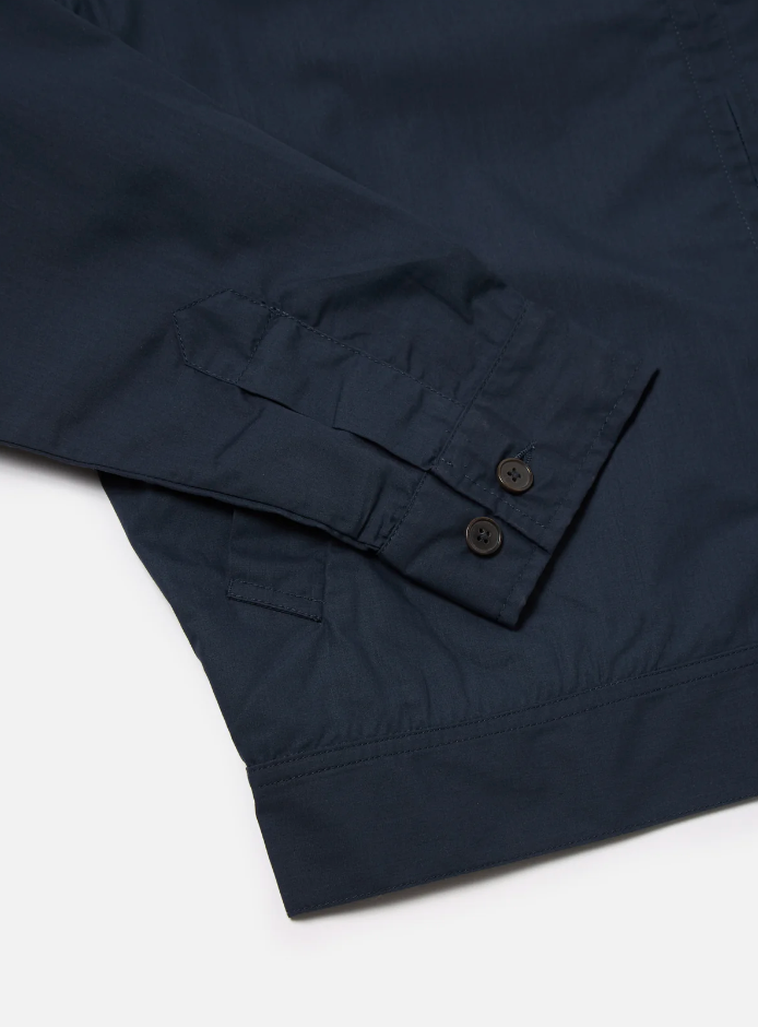 Navy boxy-fit jacket with an oversized collar, zip front, large patch pocket, welt pockets, pleated details, and an adjustable back hem.