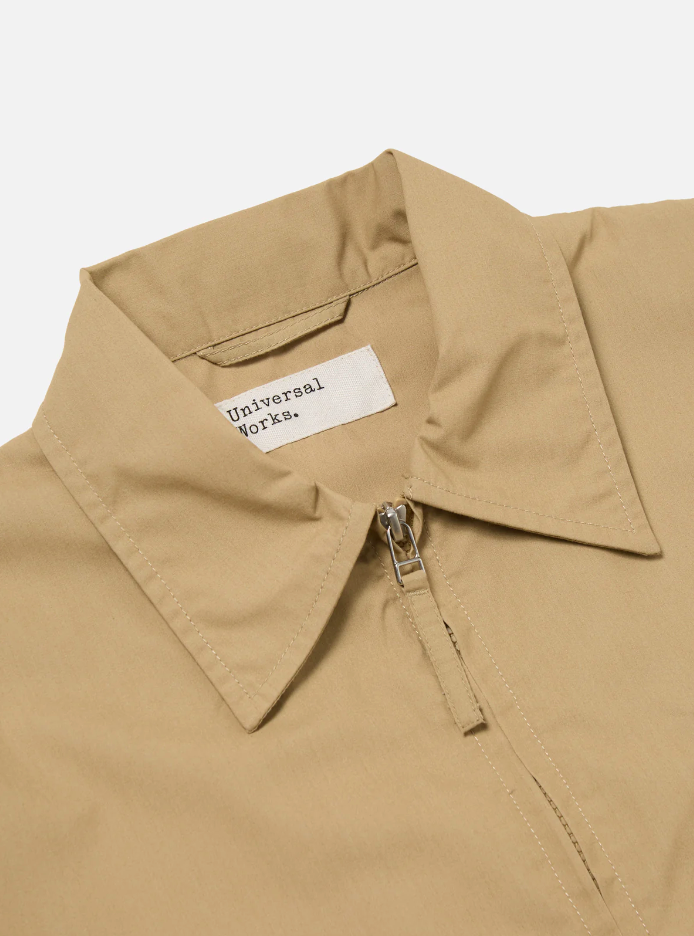 Sand-colored boxy-fit jacket with an oversized collar, zip front, large patch pocket, welt pockets, pleated details, and an adjustable back hem.
