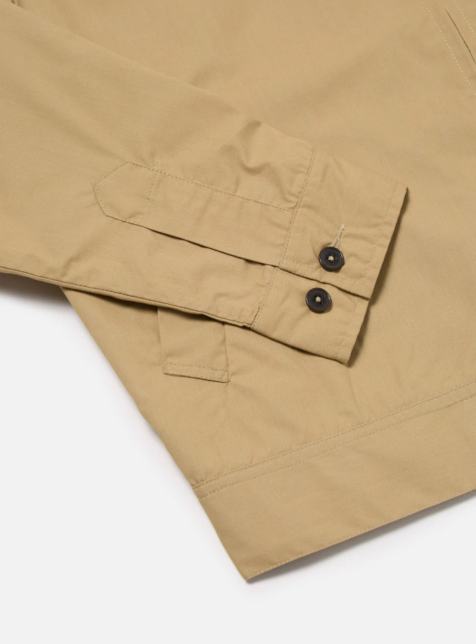 Sand-colored boxy-fit jacket with an oversized collar, zip front, large patch pocket, welt pockets, pleated details, and an adjustable back hem.