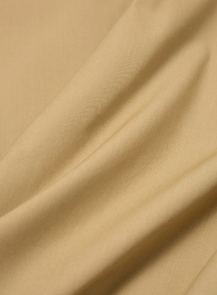 Sand-colored boxy-fit jacket with an oversized collar, zip front, large patch pocket, welt pockets, pleated details, and an adjustable back hem.