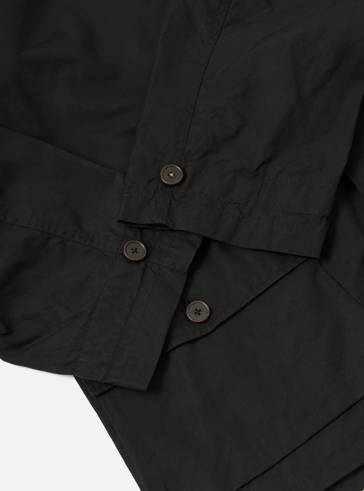 Black wax coat up close showing button details on cuffs and pockets.