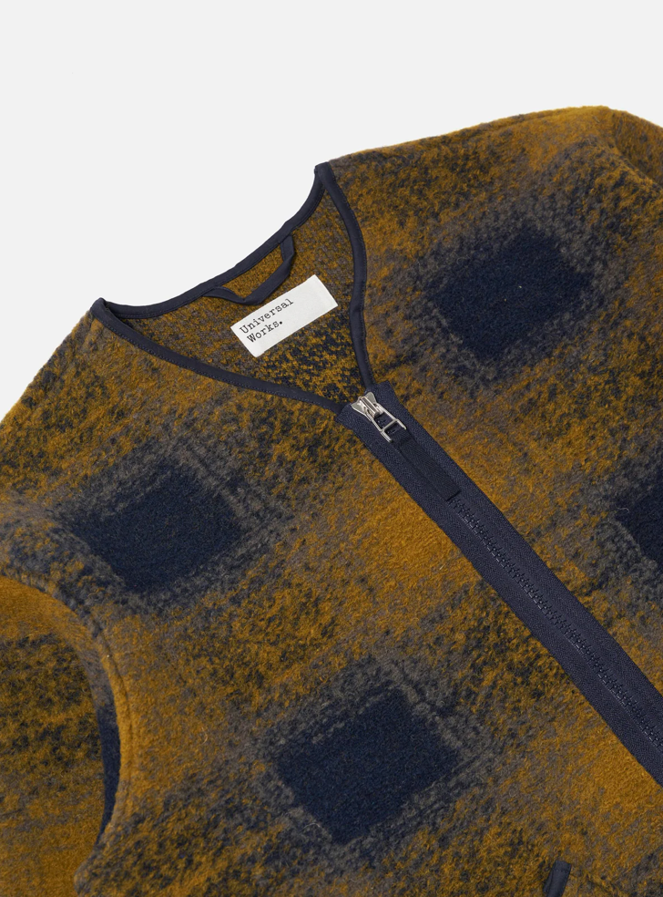 Close up of a Navy and yellow checkered pattern wool fleece zip up cardigan on a grey background.
