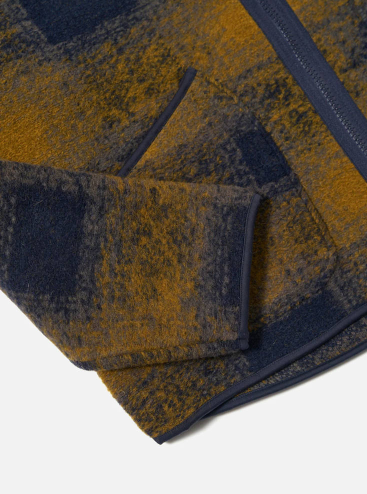 Close up of a Navy and yellow checkered pattern wool fleece zip up cardigan on a grey background.