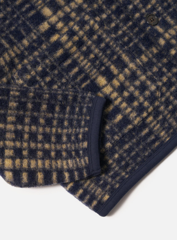 Close-up of a navy and beige checkered fabric with a button on a white background.