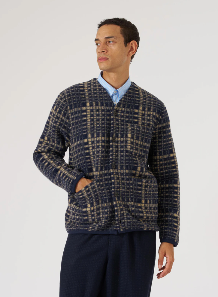 Man wearing a checkered navy and beige fleece jacket over a collared shirt on a white background.