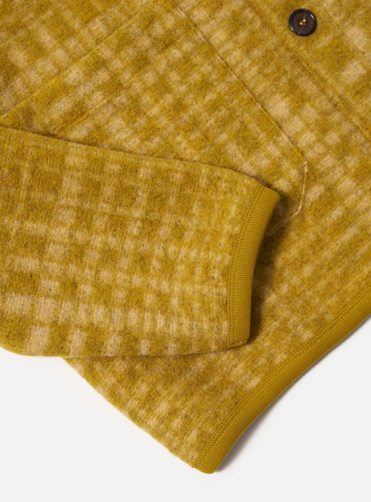 Close-up of a mustard yellow textured fabric with a button on a white background.