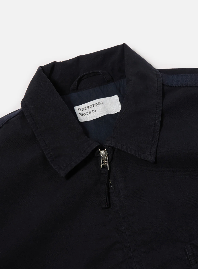 Navy cotton jacket with a double zip front, welt pockets, subtle arm stripe detail, and adjustable cuffs and waist tabs.