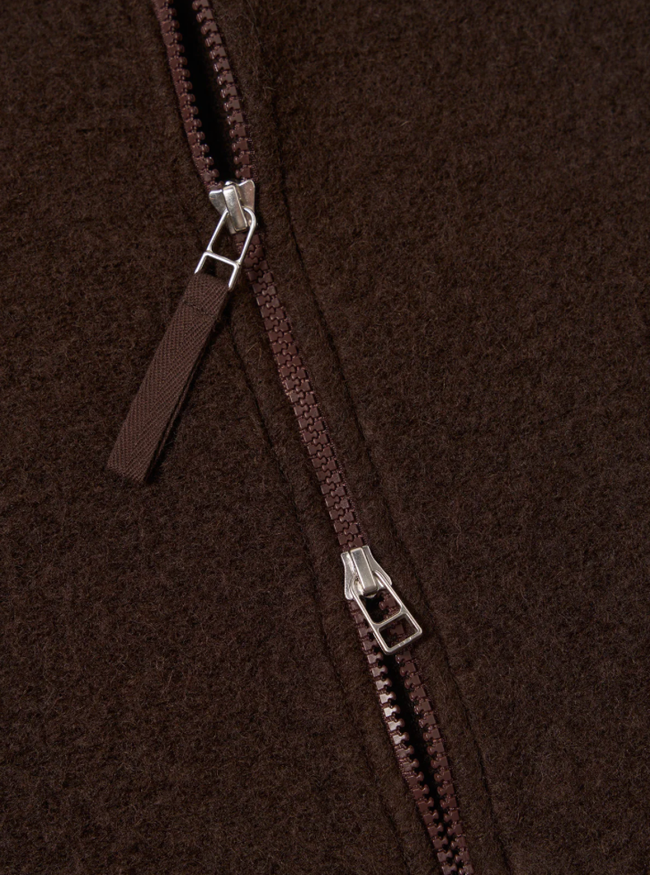 Close-up of a brown zipper on a textured brown fabric background.