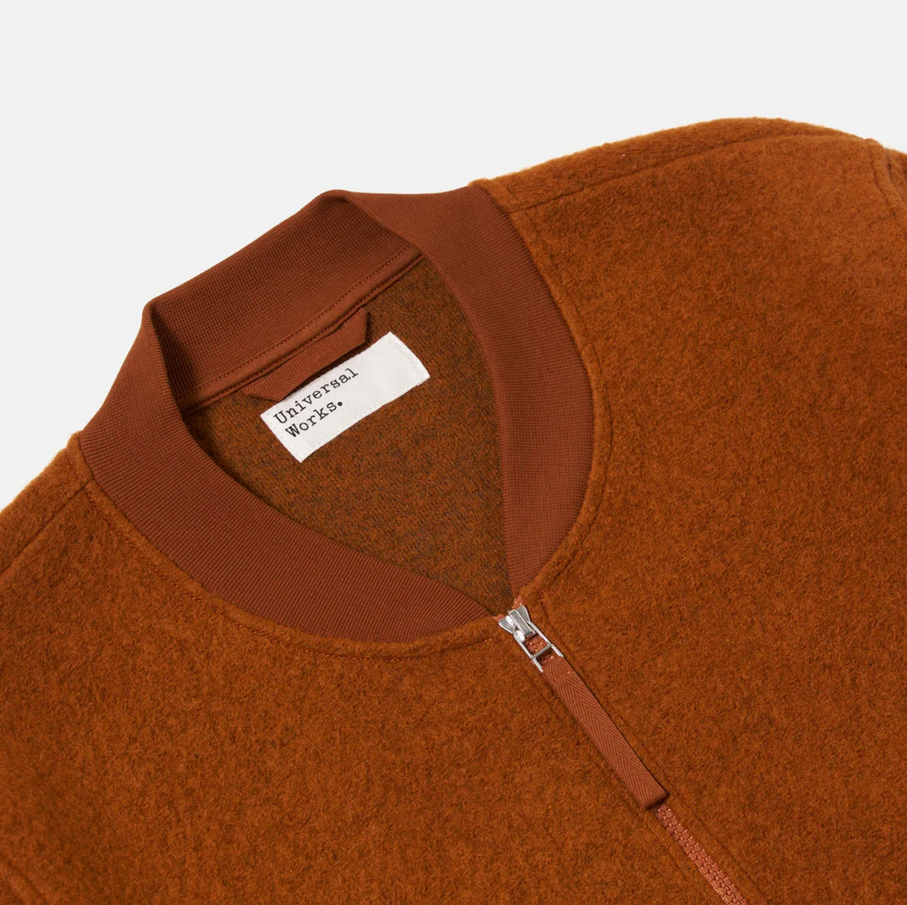 Orange fleece jacket with a visible brand label on a white background.