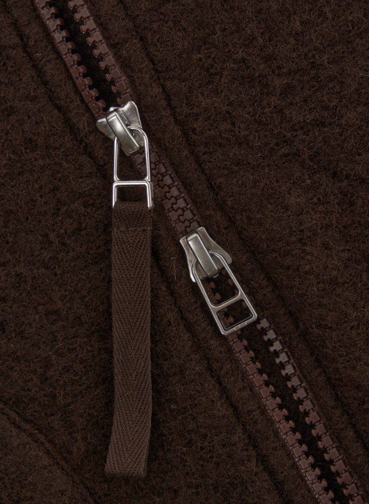 Close-up of a brown zipper on a textured fabric background.