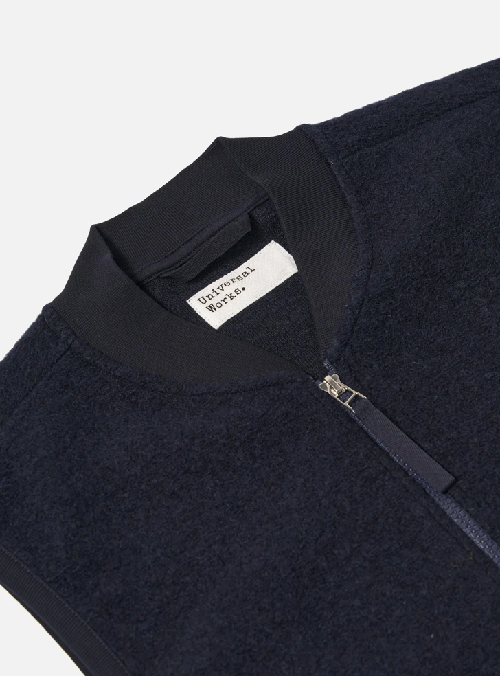Navy fleece vest with navy zipper on grey back ground.