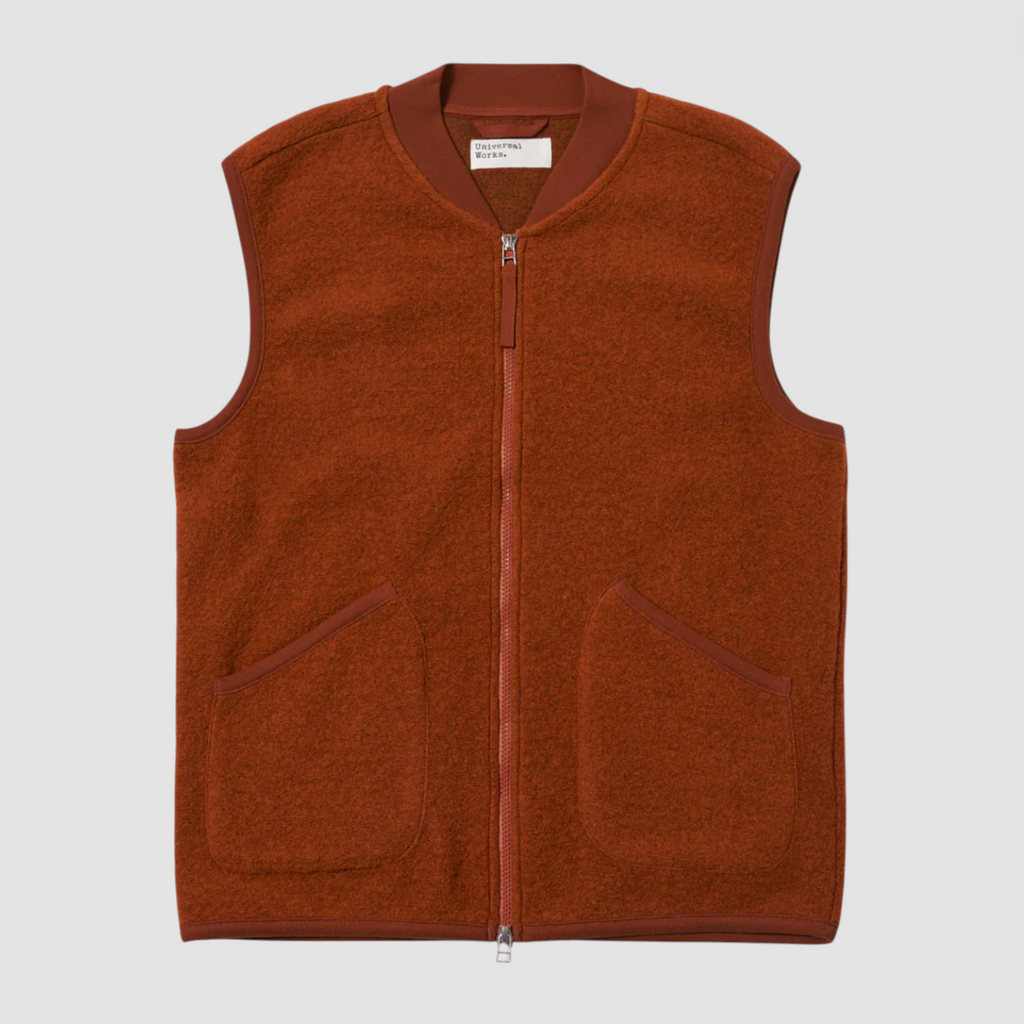 Orange fleece vest with a brand label on a light gray background.