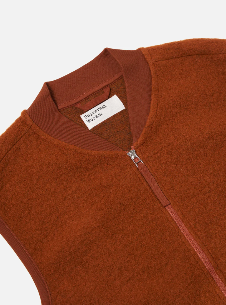 Orange fleece vest with a zipper and collar detail on a white background.