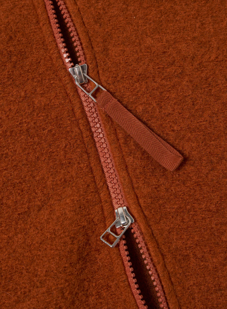 Close-up of a zipper on an orange  textured fabric.